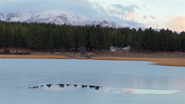 A tranquil scene of Laguna La Zeta with reflections, surrounded by forests and mountains in Patagonia, Argentina.