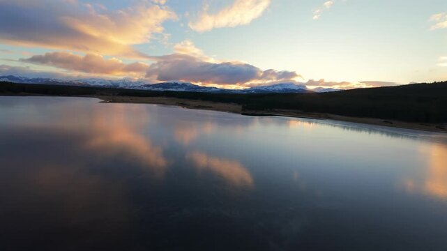 A tranquil aerial view of Laguna La Zeta reflecting colorful clouds during sunset in Esquel, Argentina.