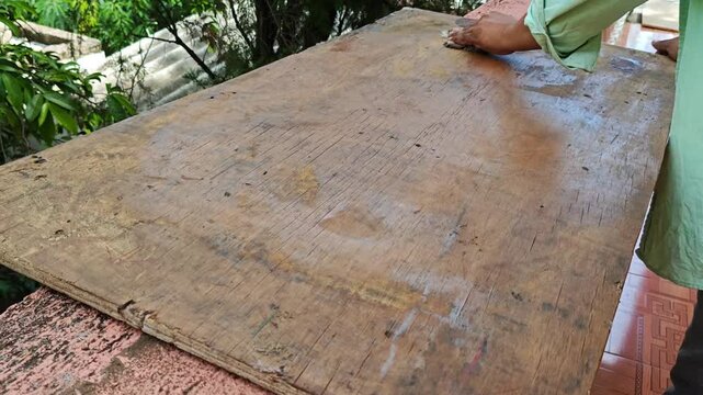 Hands of young carpenter applying protective treatment on an mdf board