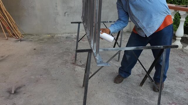 Hand painting a rustic iron frame structure with a paint brush