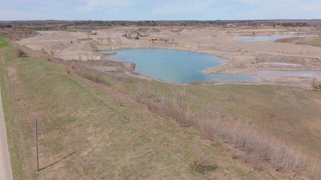 Small Lake With Aggregate And Industrial Quarry Terrain In The Background Near Caledon Village, Ontario, Canada. Aerial Ascending Shot