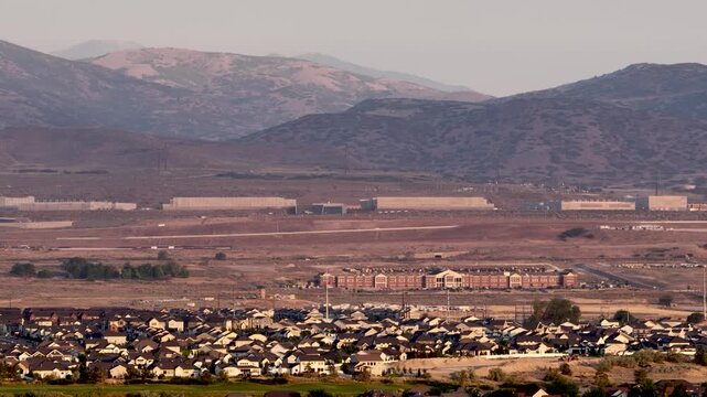 High altitude aerial view of Lehi suburbs, Camp Willimas, and the Utah Data Center against the Oquirrh mountains on a hazy day