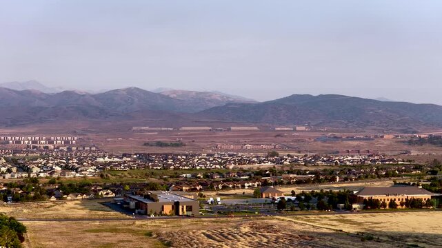 Wide angle forward aerial view of Lehi suburbs, Camp Willimas, and the Utah Data Center against the Oquirrh mountains on a hazy day