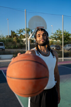 Young man holding basketball on outdoor court