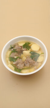 High angle view of clear soup with egg tofu and minced pork in a white bowl.