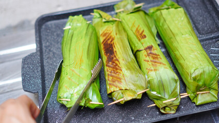 A person is cutting open a bunch of green plantains © Amjianto