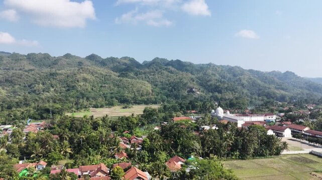 Drone view of rural temple village and fields in scenic hills.