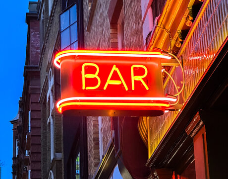 Close-Up Red Neon Bar Sign Contrasted Against Deep Blue Sky