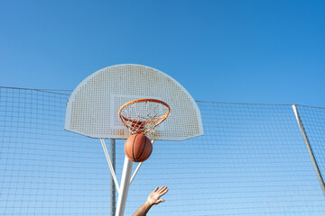 Hand shooting basketball into hoop achieving score outdoors © Nazareno