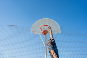 Athlete performing slam dunk during basketball game outdoor © Nazareno