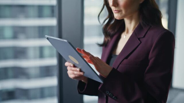 Woman fingers tapping tablet online standing by private cabinet window closeup