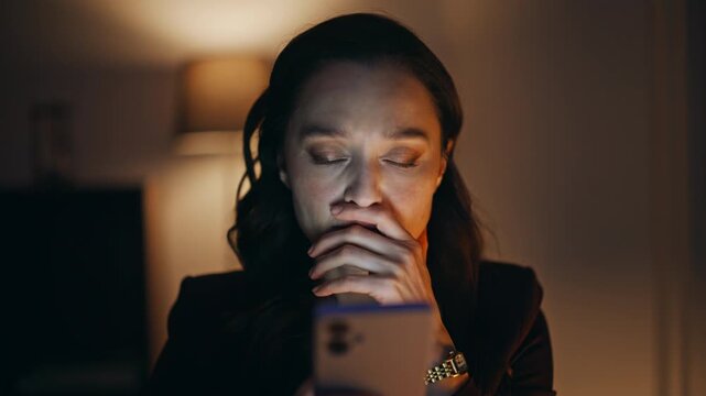 Shocked woman reading smartphone sms dark office closeup. Worried businesswoman