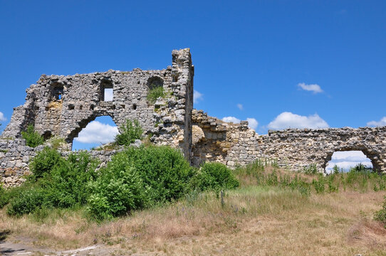 Majestic remnants of an ancient stone defensive wall, standing on a grassy hill and partially ruined, revealing picturesque arched apertures.