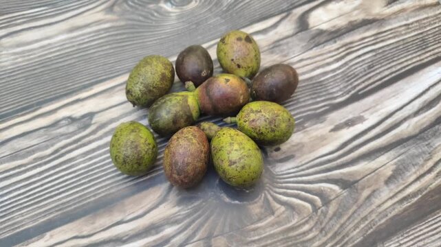 A bunch of fresh Matoa or Pometia pinnata fruit with a wooden table in the background