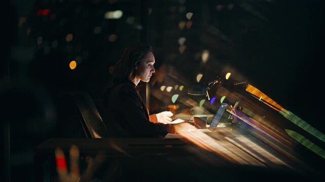 Night manager writing notes doing project working laptop overtime in lamp light