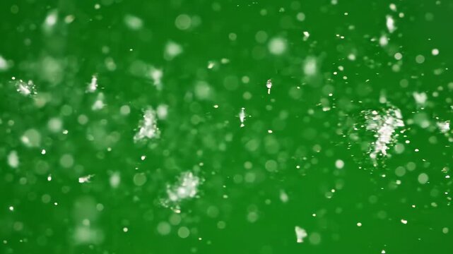 Isolated cinematic floating dust motes blowing slowly across a vibrant green screen with a smooth horizontal camera movement