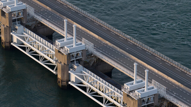 Aerial view of the Eastern Scheldt Storm Surge Barrier with concrete piers, steel gates, and road crossing the dark water in Vrouwenpolder, Zeeland, Netherlands.