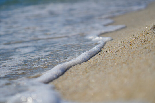 Macro view of white sea foam washing onto quartz sand beach of Is Arutas in Sardinia, Italy