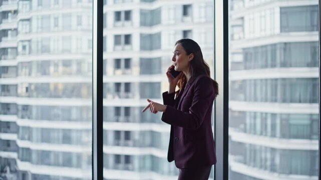 Emotional businesswoman arguing cellphone at panoramic office window closeup
