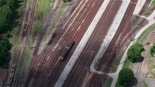Aerial view of a railway station in Hungary showing multiple parallel tracks and a locomotive moving through the platform area.