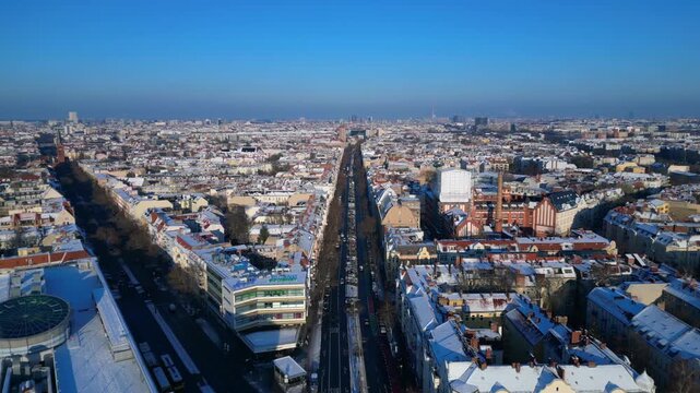 berlin city showing snow covered rooftops, buildings, and a long shopping street schloss str in winter. Marvelous aerial view dolly left panorama drone