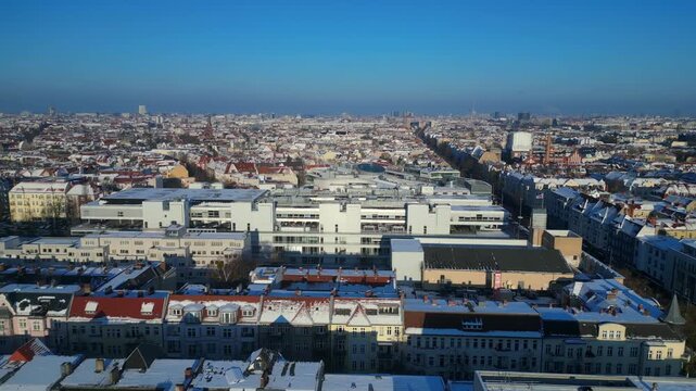 berlin city showing snow covered rooftops, buildings, and a long shopping street schloss str in winter. Beautiful aerial view dolly right panorama drone