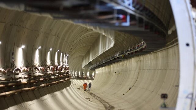Subway tunnel during construction with workers walking in it.