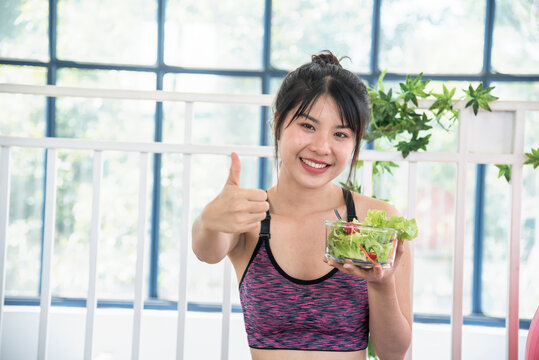 Healthy woman workout holding organic salad bowl healthy lifestyle. Wellness Asian women dressing organic green salad tomato vegetable dish. Beautiful girl healthcare vegan wellness lifestyle concept