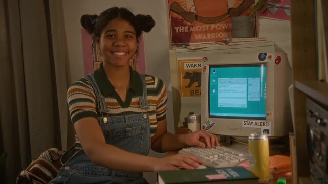 Portrait of smiling African American teenager sitting at desk and typing on retro computer. Footage is ideal for nostalgic marketing campaigns or educational videos about history of technology