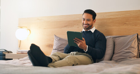 Fototapeta premium Business, man and relax in hotel room with tablet, booking flight and website for work trip. Smile, male person and employee at motel with tech, departure schedule and reservation checkin for travel