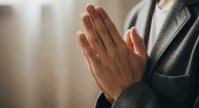 Person with hands clasped in prayer gesture indoors near window