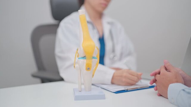 Doctor with Human Knee joint anatomy model. Osteoarthritis, Patellofemoral Pain Syndrome, Patellar Tendinitis, ACL, Anterior Cruciate Ligament, PCL, Posterior, MCL, Medial Collateral, LCL and Lateral