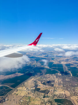 NEW SOUTH WALES, AUSTRALIA - DECEMBER 1 2024: A Qantas plane with wing tips flying over rural Australia with clear blue skies