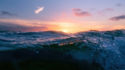 Fototapeta premium Split horizon view of a rippling ocean wave at sunset, featuring a glowing apricot sky and dark subsurface water for travel and nature concepts
