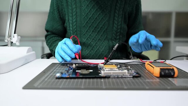 Closeup of expert soldering a green PCB board using precision tools. Ideal for electronics, circuit repair, engineering, tech