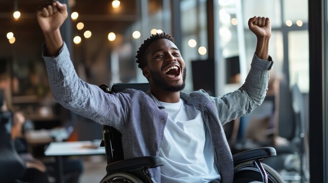 Triumph in the Wheelchair: A young Black man in a wheelchair celebrates with arms raised high in a modern office setting, embodying success and overcoming challenges with pure joy and optimism.