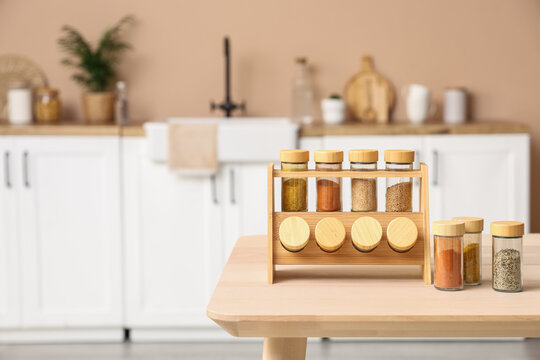 Wooden spice rack with glass jars on kitchen table