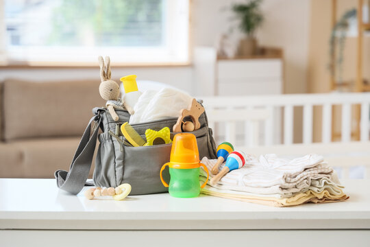 Baby essentials bag with toys and clothes on table