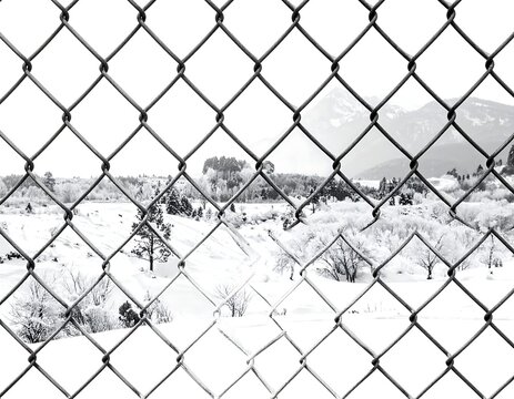 A winter landscape viewed through a chain-link fence