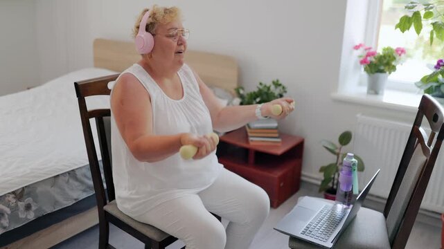 Tired senior lady taking a breath during virtual home exercise fitness at home