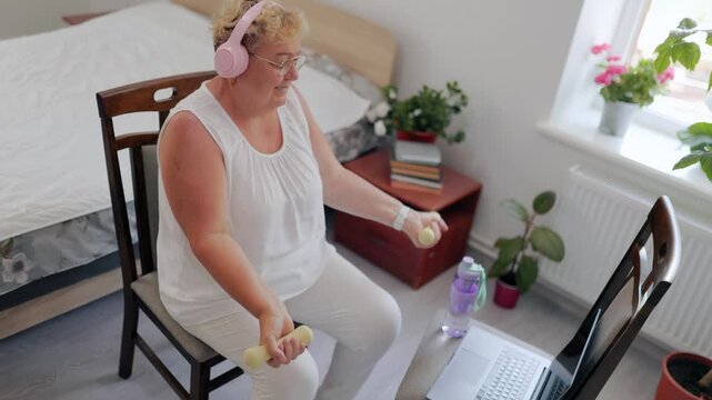 Close up of senior woman holding small yellow weights at home fitness at home