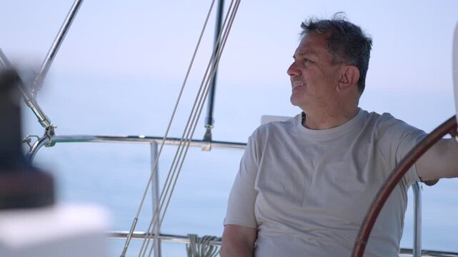 Mature skipper steering sailboat at helm