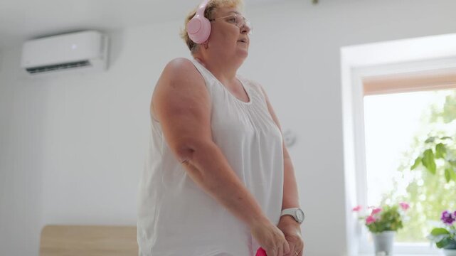 Plus size mature woman training with pink kettlebell weight at home fitness at home