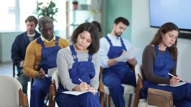  worker students takes written exam on paper in multinational group of workers in lecture hall