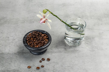 Stone bowl with roasted coffee beans and an orchid flower. © Vitalii M