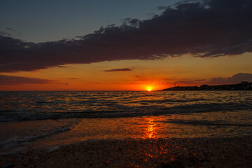 Obraz premium Orange Sunset Over the Sea With a Sandy Beach in the Foreground