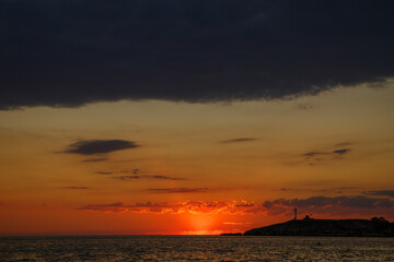 Fototapeta premium Dramatic Orange Sunset Over the Sea With Dark Clouds