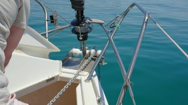 Sailor hoisting the anchor on a sailboat