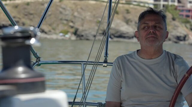 Mature skipper steering sailboat in marina