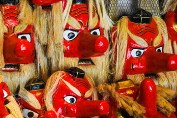 日本の伝統的な祭りで使われる赤い天狗の面が多数並ぶ様子 © MORIO
